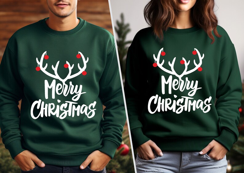 May include: Two dark green sweatshirts with the text "Merry Christmas" in white script. Above the text is a white antler design with red ornaments. The sweatshirts are a festive holiday theme.