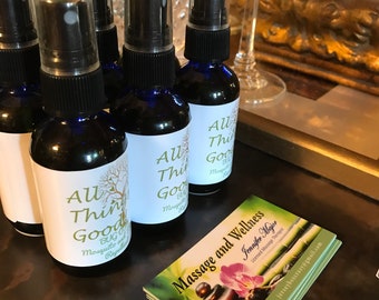 May include: Five small blue glass bottles with black caps and white labels that read "All Things Good Bug and Mosquito Repellent". The bottles are sitting on a brown surface next to a business card that reads "Massage and Wellness Jennifer Major Licensed Massage Therapist 973 828-5852 jerseybeecrazy@gmail.com".