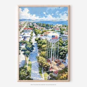 May include: Watercolor print of Stuart, Florida, featuring a detailed cityscape with a prominent water tower displaying the American flag and the city's name. The artwork captures a sunny day with a blue sky, lush greenery, and a bridge in the distance.