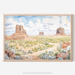 May include: Watercolor painting of a desert landscape with three large rock formations. The artwork features a dirt road, cacti, and various desert plants under a cloudy blue sky. The painting is framed in a light wood.