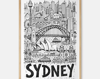 May include: A black and white line art print of the Sydney skyline in a light wood frame. The illustration features the Sydney Harbour Bridge, the Opera House, and the Luna Park face. The word SYDNEY is printed in large, bold, hand-drawn letters.