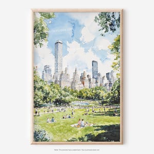 Op de afbeelding: Aquarel schilderij van een stadsparkscène met een skyline van hoge gebouwen op de achtergrond. Mensen picknicken op het groene gras. Het kunstwerk is ingelijst in een licht houten frame.