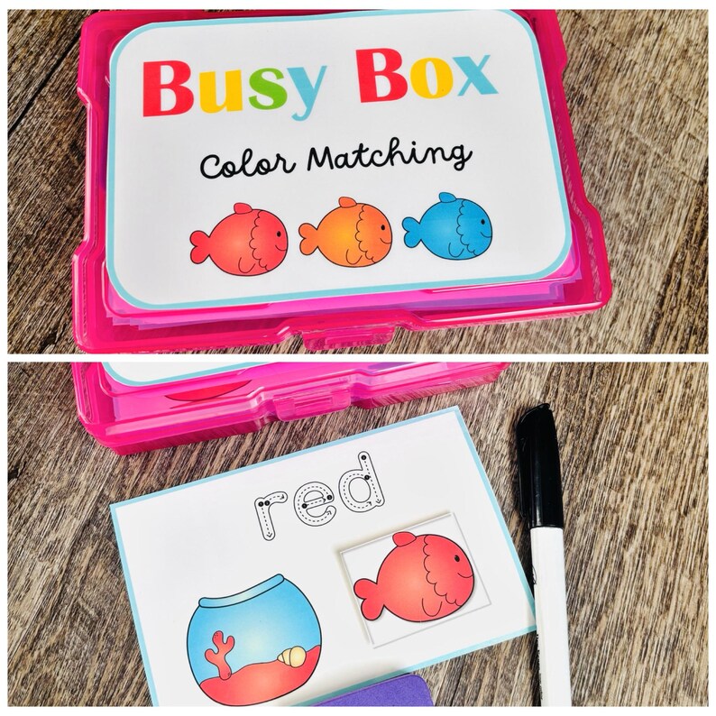 Puede incluir: Un juego de caja de pl&aacute;stico rosa etiquetado como "Busy Box Color Matching" con tarjetas que presentan ilustraciones de peces coloridos. Una tarjeta muestra un pez rojo y la palabra "red". Tambi&eacute;n se ve un marcador negro.