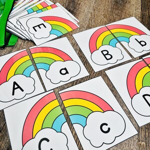 May include: Educational rainbow puzzle cards featuring the letters A, B, C, D, and E. Each card has a colorful rainbow design with a cloud. The cards are designed to be cut in half to match the letters.