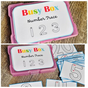 Puede incluir: Una caja de pl&aacute;stico rosa que contiene tarjetas para trazar n&uacute;meros. Las tarjetas tienen el texto "Busy Box Number Trace" y los n&uacute;meros 1, 2 y 3. Tambi&eacute;n se ven otras tarjetas con n&uacute;meros.