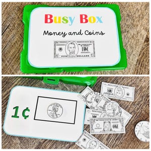Puede incluir: Una "Busy Box" verde y blanca para dinero y monedas. La caja contiene dinero de juguete, incluidos billetes de cinco y un d&oacute;lar, y un centavo. El texto "Money and Coins" se muestra en la caja.