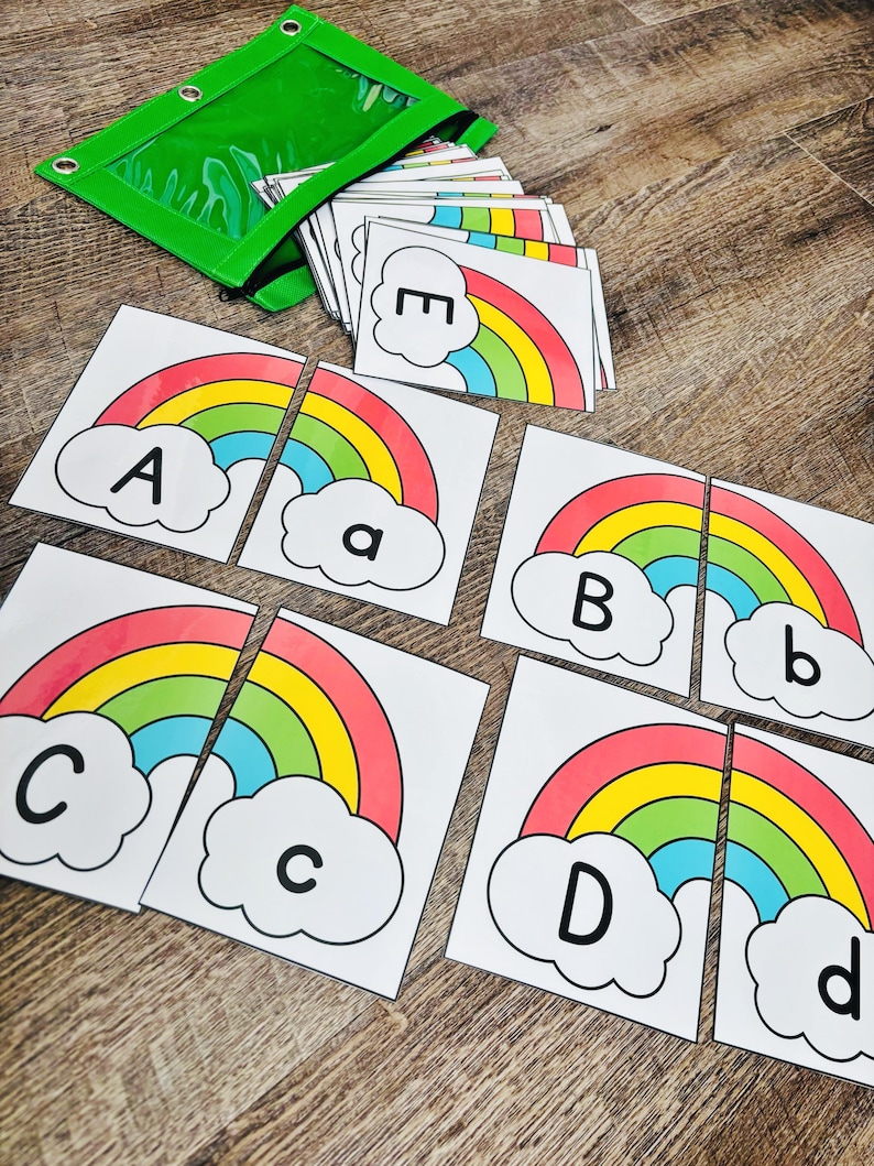 May include: Educational alphabet matching game featuring rainbow-themed cards. Each card has a colorful rainbow design with a letter, both uppercase and lowercase. A green zippered pouch holds the cards, perfect for learning.