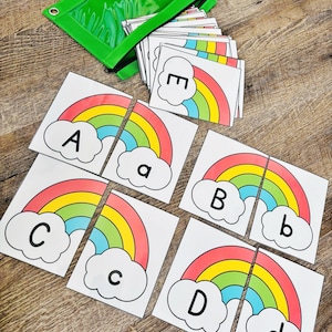 May include: Educational alphabet puzzle cards featuring colorful rainbows and clouds. Each card has a letter, both uppercase and lowercase, with a corresponding rainbow image. A green zippered pouch holds the cards.