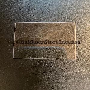 Puede incluir: Un quemador de incienso de vidrio transparente, con el texto "BakhoorStoreIncense" impreso en la parte inferior.