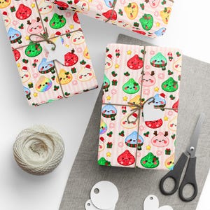 May include: Wrapping paper with a repeating pattern of kawaii-style dumplings wearing holiday accessories like Santa hats and scarves, interspersed with small gifts, stars, and snowflakes on a background of light pink vertical stripes.