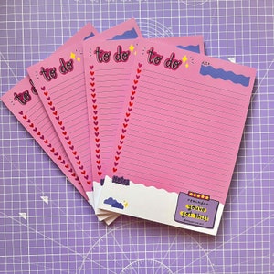 May include: A set of four pink to-do list notepads with a white border. Each notepad has a pink and white heart border, the words "to do" in pink, and a yellow star. The bottom notepad has a white cloud with a yellow star, the words "Notes" in black, and a reminder sticker that says "reminder: you've got this!" in black and white.