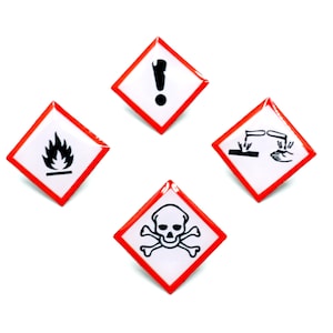 Könnte beinhalten: Vier Gefahrenwarnschilder mit roten Rändern und weißem Hintergrund. Die Etiketten zeigen schwarze Symbole: eine Flamme, ein Ausrufezeichen, ein ätzendes Symbol und einen Totenkopf. Auf weißem Hintergrund angeordnet.