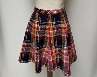 May include: A red, yellow, and black plaid skirt with a flared silhouette. The skirt is on a white mannequin.
