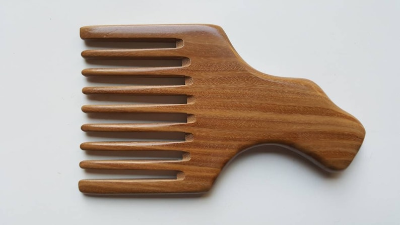 A wooden pick comb with a curved handle and nine teeth. The comb is made of light brown sandalwood with a natural grain pattern.