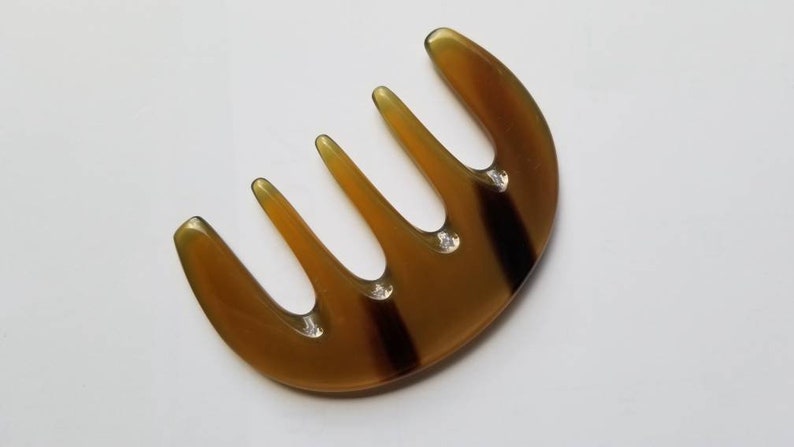 Polished translucent amber yak horn five-tooth comb, flat lay overhead showing natural color variation — Arakicrafts