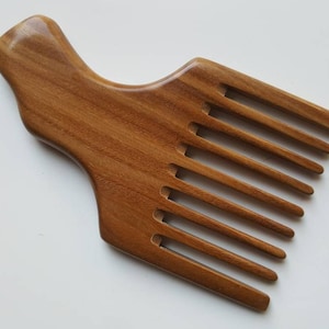 A wooden pick comb with a unique handle design. The comb has nine teeth and is made of light brown sandalwood.  Gift for love ones who grows long hair!