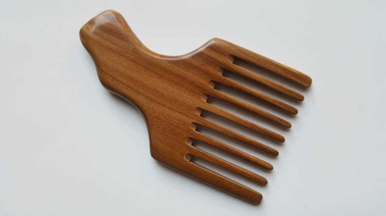 A wooden pick comb with a unique handle design. The comb has nine teeth and is made of light brown sandalwood.  Gift for love ones who grows long hair!