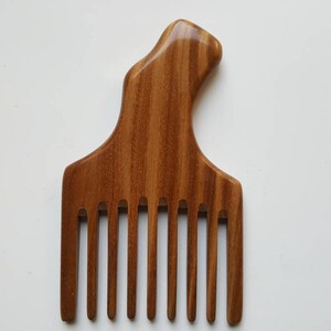 A wooden pick comb with a unique handle design. The comb has 9 teeth and is made of brown sandalwood with a striped pattern.  Beautiful one of kind natural comb and great gift. Comes with fabric gift bag.