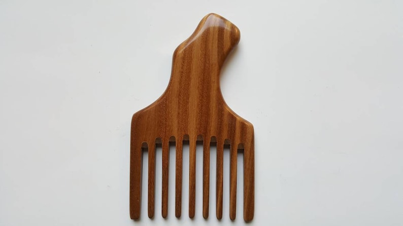 A wooden pick comb with a unique handle design. The comb has 9 teeth and is made of brown sandalwood with a striped pattern.  Beautiful one of kind natural comb and great gift. Comes with fabric gift bag.
