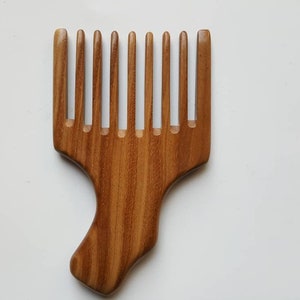 A sandalwood pick comb with a nice curved handle and a row of nine long teeth. This comb has  a natural grain pattern and is one of a kind piece.  Great gift for long hair lovers!