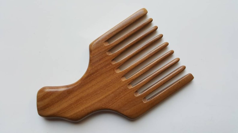 A sandalwood pick comb with a curved handle and nine teeth. The comb  has a smooth finish and comes with a fabric gift bag.  Gift for her!