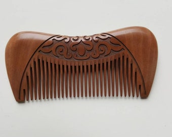 May include: A brown wooden comb with a carved design on the top. The comb has a curved shape and is made of natural wood.