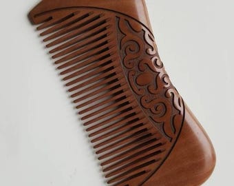 Pode incluir: Um pente de madeira castanha com um cabo curvo e liso e uma série de dentes finos e uniformemente espaçados. O cabo apresenta um padrão intrincado esculpido em baixo-relevo com formas orgânicas e rodopiantes que contrastam com a madeira.