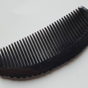 May include: A black plastic comb with a curved handle and fine teeth.