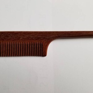 A rat tail wooden comb with a long, thin handle. The comb is brown and has a natural wood finish. Anti-static, Eco-friendly gift