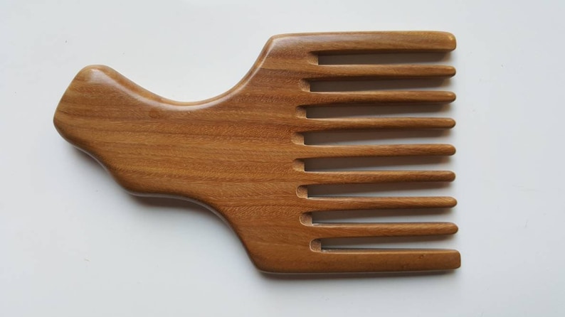 A wooden pick comb with a unique handle design. The comb has nine teeth and is made of light brown sandalwood.  Gift for him who grows long hair!