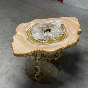 May include: A gold and white resin table with a crystal geode center and a gold honeycomb base.