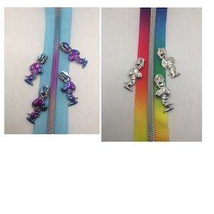 May include: Two zipper pulls with a rainbow iridescent finish and two zipper pulls with a silver finish. Each zipper pull features a small cartoon dog charm.