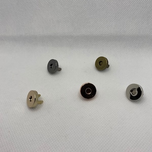 May include: Five magnetic snaps in different finishes: silver, gold, rose gold, black, and antique brass.
