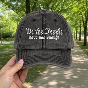 May include: A distressed black baseball cap with the embroidered text "We the People have had enough" in white script. The cap has a curved brim and an adjustable strap.