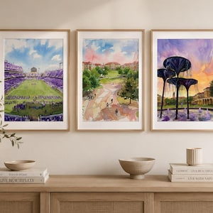 May include: Three framed watercolour prints displayed side-by-side. The left print shows a football stadium with purple seating and a green field. The centre print depicts a campus lawn with walkways and buildings. The right print features a fountain.