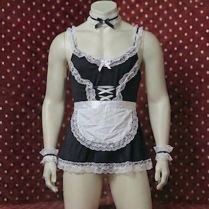 May include: Black and white maid costume with lace trim, displayed on a mannequin. The outfit includes a dress, apron, choker, and wrist cuffs. The dress features a corset-style front and white lace detailing.