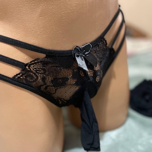 K&ouml;nnte beinhalten: Schwarze Spitzenunterw&auml;sche mit Schleifendetail und Riemen-Design. Die Unterw&auml;sche ist aus durchsichtigem Stoff und hat ein zartes Spitzenmuster.