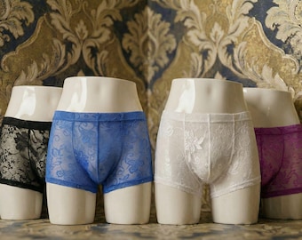 May include: Four pairs of underwear in black, blue, white, and purple, displayed on mannequin torsos. The underwear features lace detailing. The background is a patterned wallpaper with gold and blue tones.