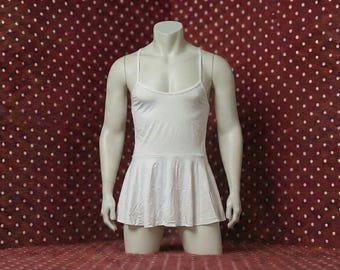 May include: A white leotard-style garment with spaghetti straps and a flared skirt, displayed on a mannequin. The fabric appears to be lightweight and slightly textured. The mannequin is set against a red background with white polka dots.
