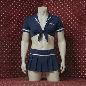 Peut inclure: Ensemble deux pièces bleu marine sur mannequin. Le haut est une chemise à manches courtes à nouer, avec une bordure blanche et le mot "JALLICK" imprimé sur la poitrine. La jupe plissée assortie a une bordure blanche et des boutons décoratifs.