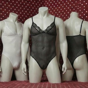 Könnte beinhalten: Drei Schaufensterpuppen präsentieren Dessous. Die mittlere Schaufensterpuppe trägt einen schwarzen, vertikal gestreiften Body mit Spitzentrimm. Die anderen beiden Schaufensterpuppen zeigen einen weißen, vertikal gestreiften Body und einen schwarzen, vertikal gestreiften Body.