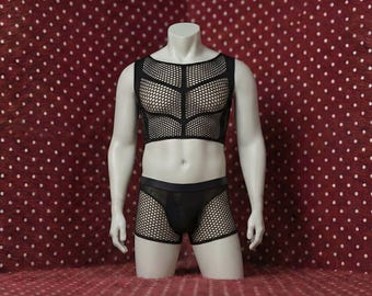 May include: A black mesh crop top and matching shorts set displayed on a mannequin. The top features a geometric design, and the shorts have a mesh overlay. The mannequin is set against a red background with white polka dots.