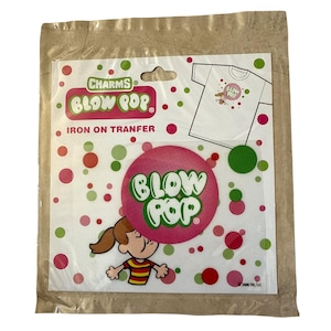 May include: A package containing a "Blow Pop" iron-on transfer. The transfer features the words "Blow Pop" in green and pink, along with a cartoon image of a girl. The package also includes a design for a t-shirt.