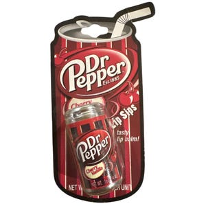 May include: A Dr Pepper Cherry Vanilla Lip Sips lip balm in a clear cylindrical container, packaged on a cardboard backing shaped like a soda can with a straw. The packaging features red and white stripes, cherry graphics, and the text Dr Pepper.