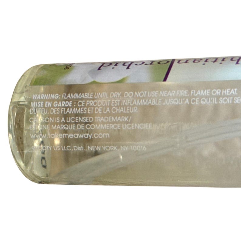 Puede incluir: Una botella cil&iacute;ndrica transparente con una etiqueta con texto y un dise&ntilde;o floral. La etiqueta incluye advertencias sobre inflamabilidad y el sitio web www.takemeaway.com. La botella est&aacute; parcialmente llena de un l&iacute;quido transparente.