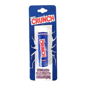May include: A blue and white Nestle Crunch lip balm on a blue cardboard backing. The lip balm tube is blue with the word "CRUNCH" in red and white. The packaging reads "Milk Chocolate Scented Lip Balm" and "NET WT .15 OZ (4.2 G)."