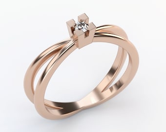May include: A rose gold ring with a single diamond set in a square prong setting. The ring band is double-banded and twisted.