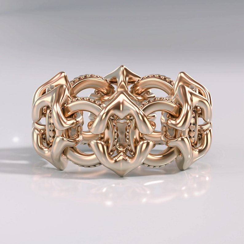 May include: A gold ring with a detailed, intricate design. The ring is made up of a series of interlocking loops and curves, creating a complex and elegant pattern.