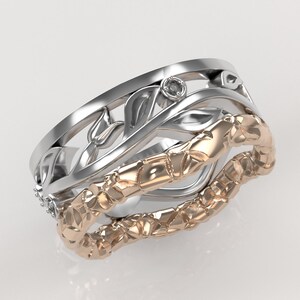 Puede incluir: Un anillo de plata y oro rosa con un delicado diseño floral y un pequeño acento de diamante. El anillo está hecho de dos bandas, una con una superficie texturizada y la otra con un diseño más intrincado.