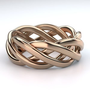 Puede incluir: Un anillo de color dorado con un diseño tejido. El anillo está hecho de múltiples hebras de metal que se entrelazan para crear un patrón complejo.